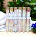 Whole Self Aromatherapy's bath salts in test tubes on a table with white linens, framed by greenery in back and a blue flower to the right.